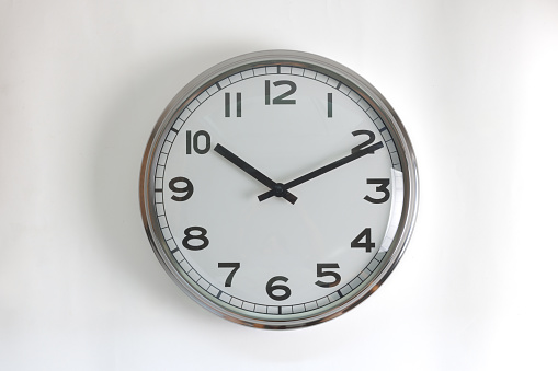 A white round shape wall clock face with clock black hands showing the time of 10:10 isolated in white background. Short hand at 10 o'clock and long hand at number 2 as V shape.