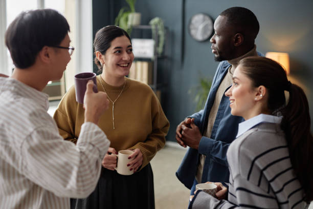 istock Four Cheerful Adults Enjoying Coffee Break in Office 2115292100