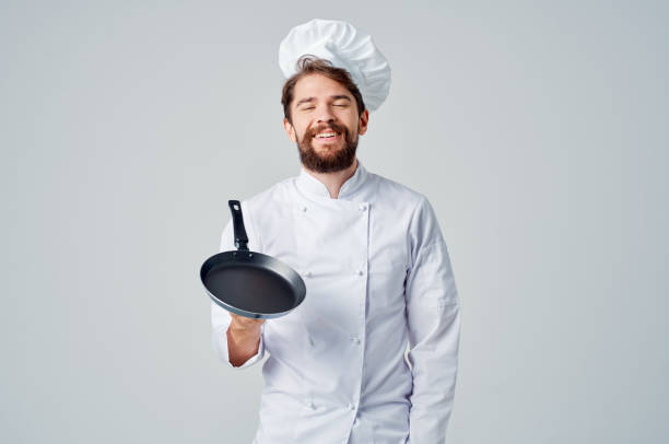 istock a man in a chef's uniform pan cooking kitchen Professional 2115295795