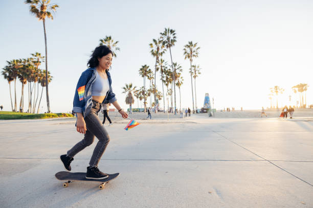istock Woman skating to the Pride holding rainbow flags 2115304113