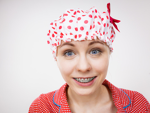 Funny happy woman after shower wearing pink pajamas and dotted bathing cap