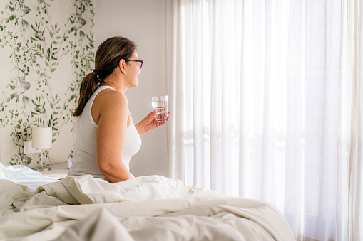 Female sitting on bed  drinking water in the morning