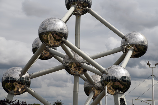 The Atomium Monument In Brussels with dark dramatic sky and with National Flag on the top