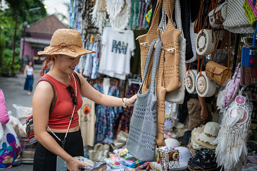 A Young, Beautiful Asian Female Tourist Enjoys Street Shopping in Bali's Bustling Bazaar