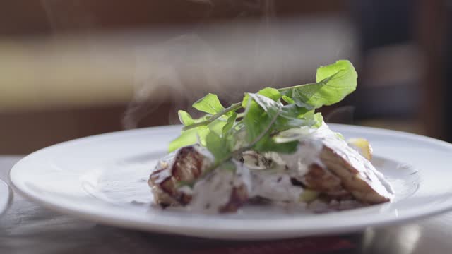 Grilled beef steak with cream sauce and vegetables served on plate with hot steam, cinematic isolated slow motion shot