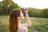 charming woman with a vine of grapes outdoors in a meadow