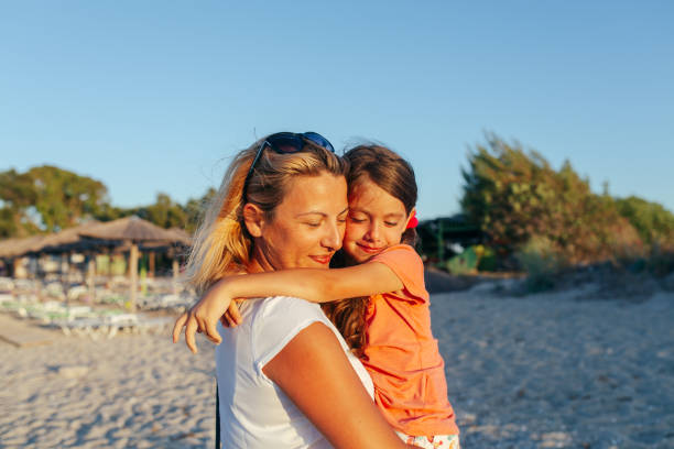 Mother sharing bonding moment with her daughter , embracing on the beach