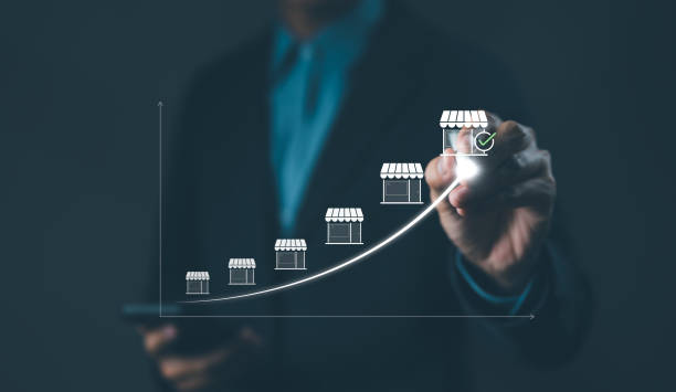 Franchise concept. Franchise Business Growth and Expansion Strategy Visualization. Entrepreneur visualizing franchise growth trajectory with increasing store icons on a digital upward trend graph. Franchise concept. Franchise Business Growth and Expansion Strategy Visualization. Entrepreneur visualizing franchise growth trajectory with increasing store icons on a digital upward trend graph. chain store stock pictures, royalty-free photos & images