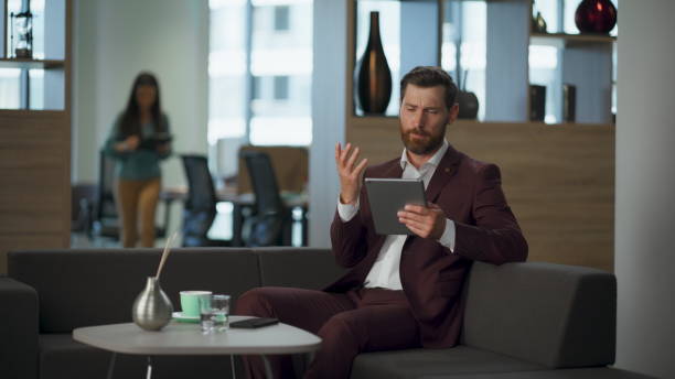 istock Annoyed entrepreneur working tablet computer in office. Tired man swiping pad 2115429859