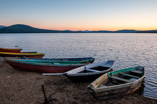 Wooden boats on the shore of a lake on a sunset summer evening