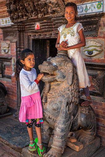 Little girls playing in Hindu temple on the Durbar square of Bhaktapur. Bhaktapur is an ancient town in the Kathmandu Valley and is listed as a World Heritage Site by UNESCO for its rich culture, temples, and wood, metal and stone artwork.