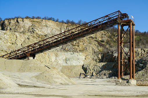 Huge rusty metal structures for transporting rocks in a dolomite mining quarry, gravel crushing, sorting, conveying, blue sky background