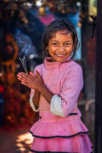 Portrait of little Nepali girl praying in an ancient temple in Bhaktapur. Bhaktapur is an ancient town in the Kathmandu Valley and is listed as a World Heritage Site by UNESCO for its rich culture, temples, and wood, metal and stone artwork.