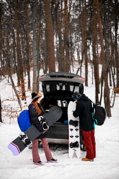 Two happy little twin kids brother and sister sit in the open car by sledge, baggage trunk ready to enjoy alpine vacation