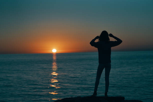 woman gesturing with her hands and sunset sea landscape beach. High quality photo