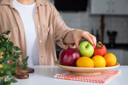 Woman taking apple from fruit bowl