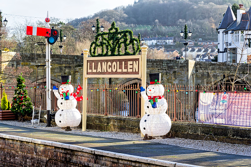 View of Llangollen station at Christmas in the centre of Llangollen, UK .  Father Christmases can be seen on the station platform.  People can be seen on the bridge.