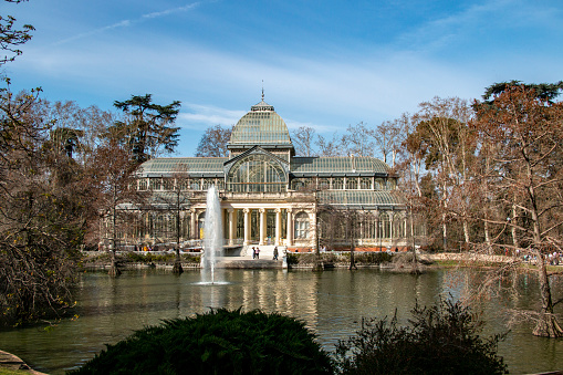 Crystal palace in El Retiro park in the city of Madrid, built in steel and glass next to a beautiful pond