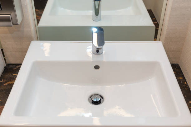 A white square bathroom sink with a faucet is positioned on top of a stonecounter