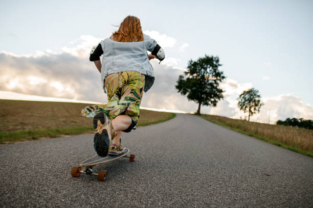 istock Gray day ride. Girl on longboard, viewed from behind. 2115489375