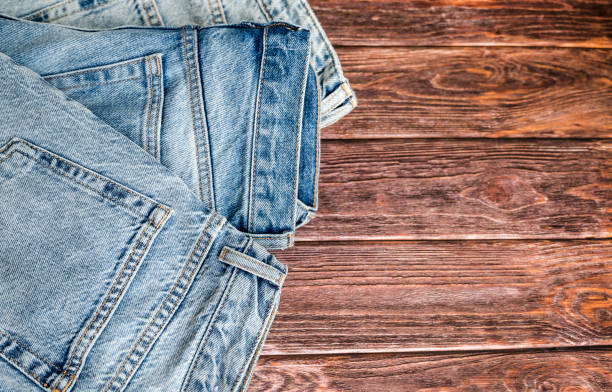 istock Blue denim jeans on wooden background 2115498366