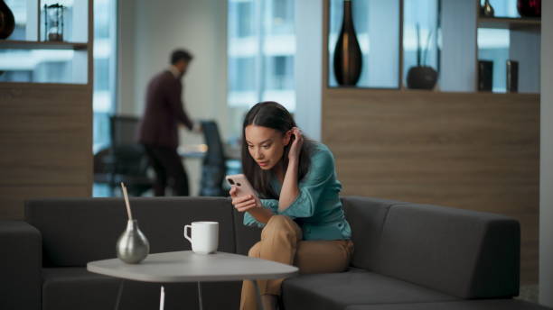 istock Happy lady watching smartphone at office sofa. Woman rejoicing success alone 2115498906