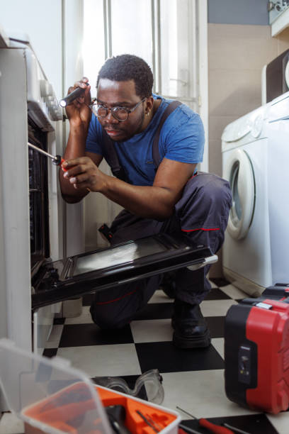 istock Young handyman repairing the oven in the kitchen 2115500544