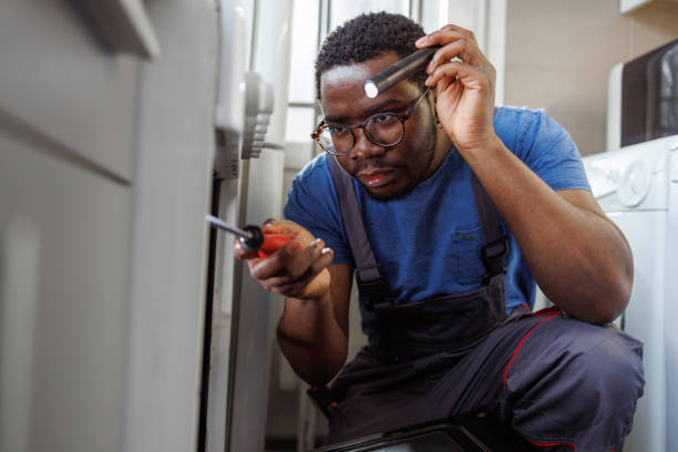 istock Young handyman repairing the oven in the kitchen 2115501078