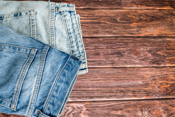 istock Blue denim jeans on wooden background 2115501450