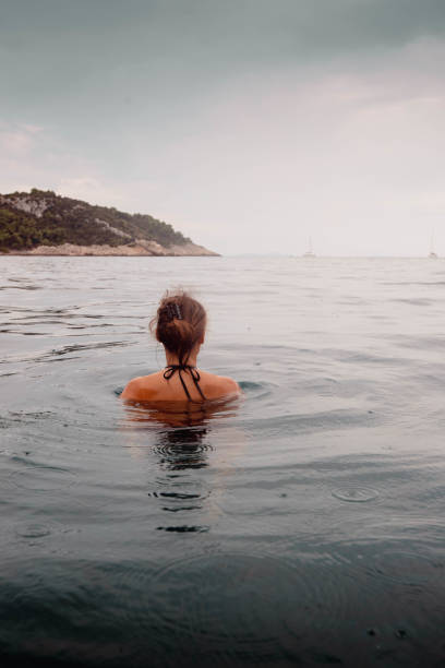 istock Young woman floats on sea 2115534395