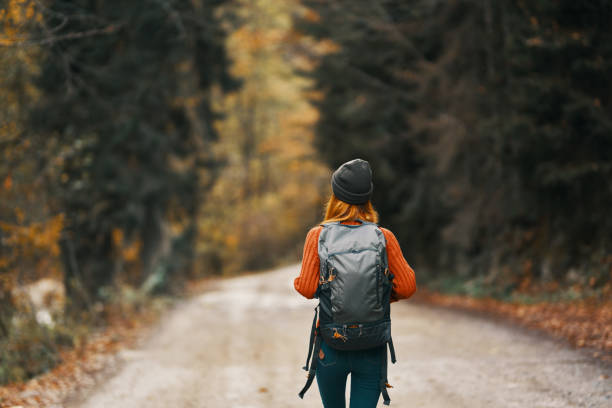istock Traveler with a backpack in the forest on the road in autumn trees model 2115555438