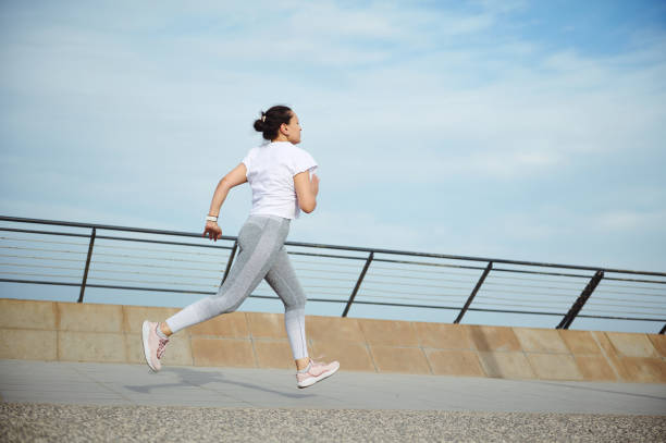 istock View from the back to a sportswoman, runner jogger athlete doing cardio workout, running outdoors on the city bridge 2115559129
