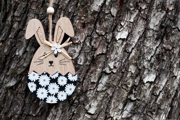 istock Happy Easter greeting card with place for text. Decorative wooden toy Easter bunny on background of tree bark. 2115581868