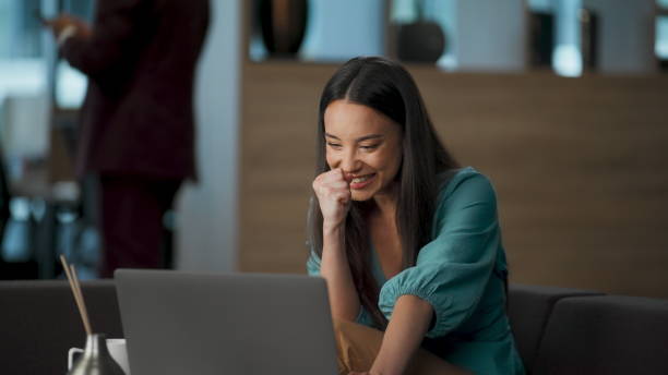istock Cheerful girl sitting sofa rejoicing with laptop. Smiling manager looking screen 2115612361