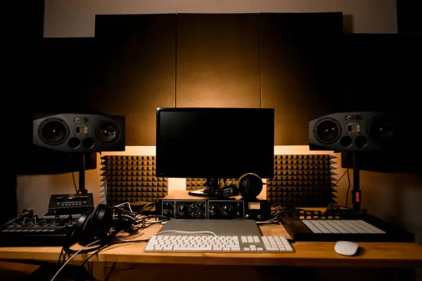 Recording studio desk with monitor and all necessary equipment for music recording, acoustic system, headphones, Macbook, computer, midi-controller, synthesizer