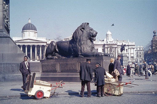 London, England, UK, 1959. Street scene with street sweepers, tourists and Londoners at famous Trafalgar Square in the City of London