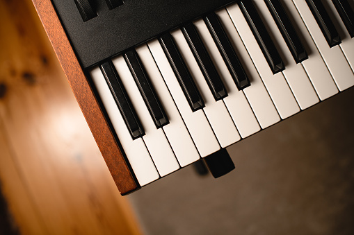 Close-up top view of part of the synthesizer keys on a blurred floor background. Focus on the foreground