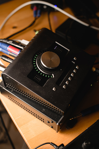 Close-up of an audio interface on a desktop with cables connected to other equipment. Professional recording studio equipment. Side view