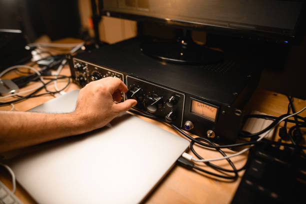 istock Close-up of a man's hand turning a control on a microphone preamplifier 2115647025