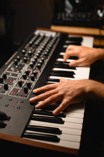 istock Focus on the foreground as a musician plays a professional synthesizer in a recording studio 2115652744