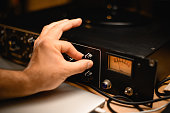 Close-up of a man's hand carefully turning a knob on a microphone preamplifier