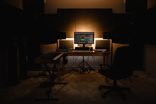 Sound recording worker's office with all the necessary equipment for work, the back wall is partially lit by square lamps