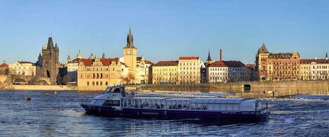 Prague, Czech Republic, January 28, 2024: A cruise ship sails on the Vltava River in the Czech capital on a sunny winter day. In the background is the Charles Bridge.