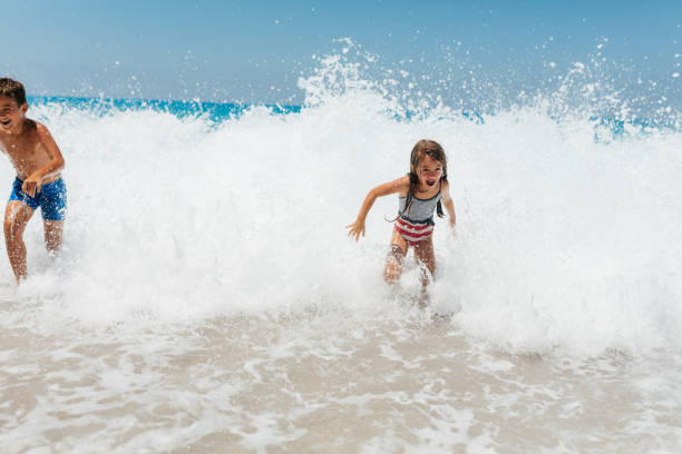 istock Playful children having fun playing with the waves 2115669966