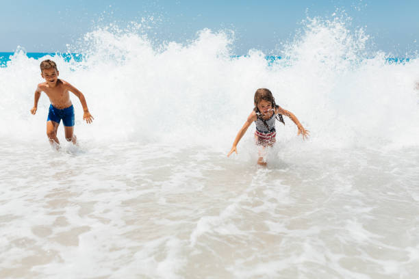 istock Playful children having fun playing with the waves 2115670316