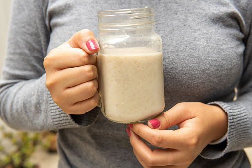 close-up of woman's hands with a jug of smoothie in the morning