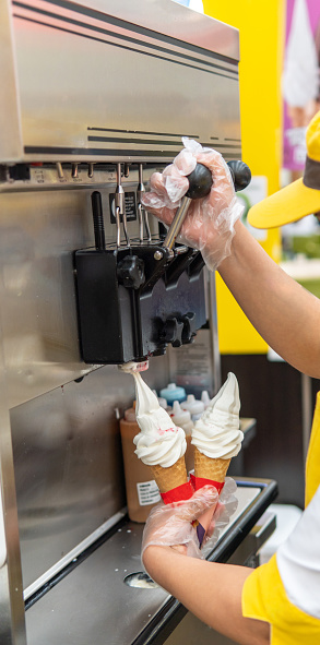hands dispensing ice cream from an ice cream machine in a shopping center