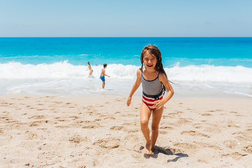 Girl having fun exit from the waves on a beautiful Greek Lefkada island