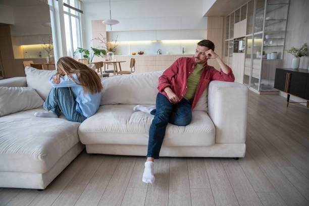 istock Upset unhappy crying wife sitting on sofa, turning back to indifferent husband neglecting female 2115671906
