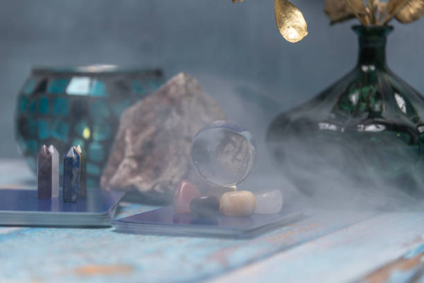 A serene tarot card reading space with assorted healing crystals, a candle lantern, and a geode on a weathered wooden surface